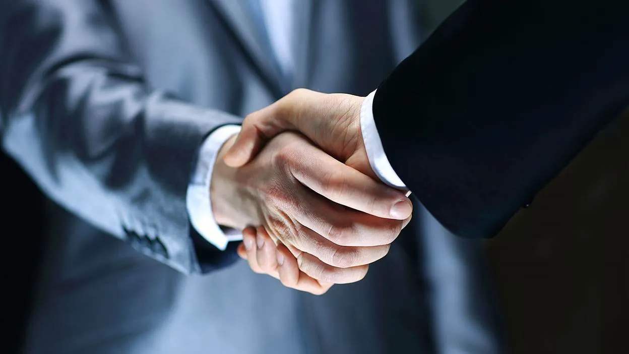 Deux personnes en costume se serrent la main